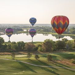Hot air balloons floating over a golf course with a reflective lake in Windsor, Colorado