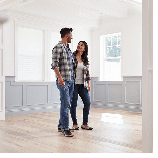 Prospective Homebuyers Exploring Empty Room Happy couple standing inside a spacious empty room with hardwood floors in a house viewing